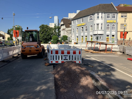 Hier sieht man das Baustellenende vor der Kreuzung Lisdorfer Straße. Ein Teil des GRabens ist schon wieder mit Kies verschlossen. Der letzte Teil kurz vor der Kreuzung ist noch offen und von Absperrungen umrahmt.